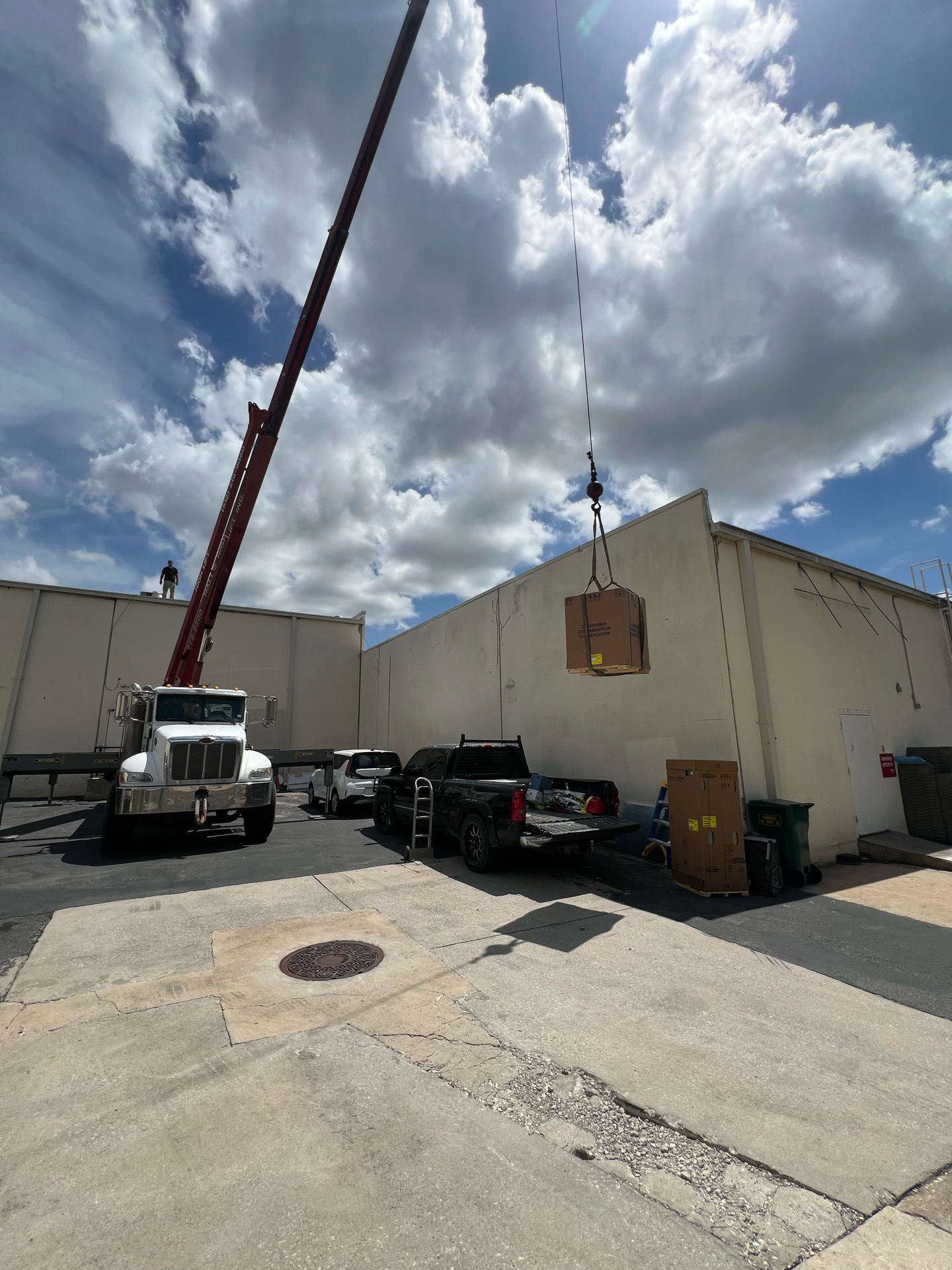 Crane hoisting HVAC equipment beside a commercial building during installation